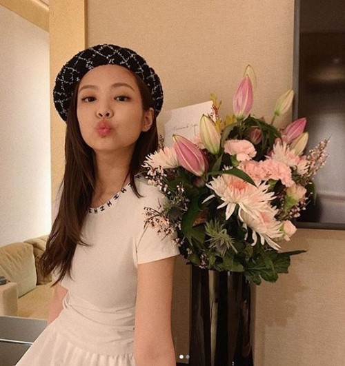 A K-pop celebrity called Jennie is standing besides flower